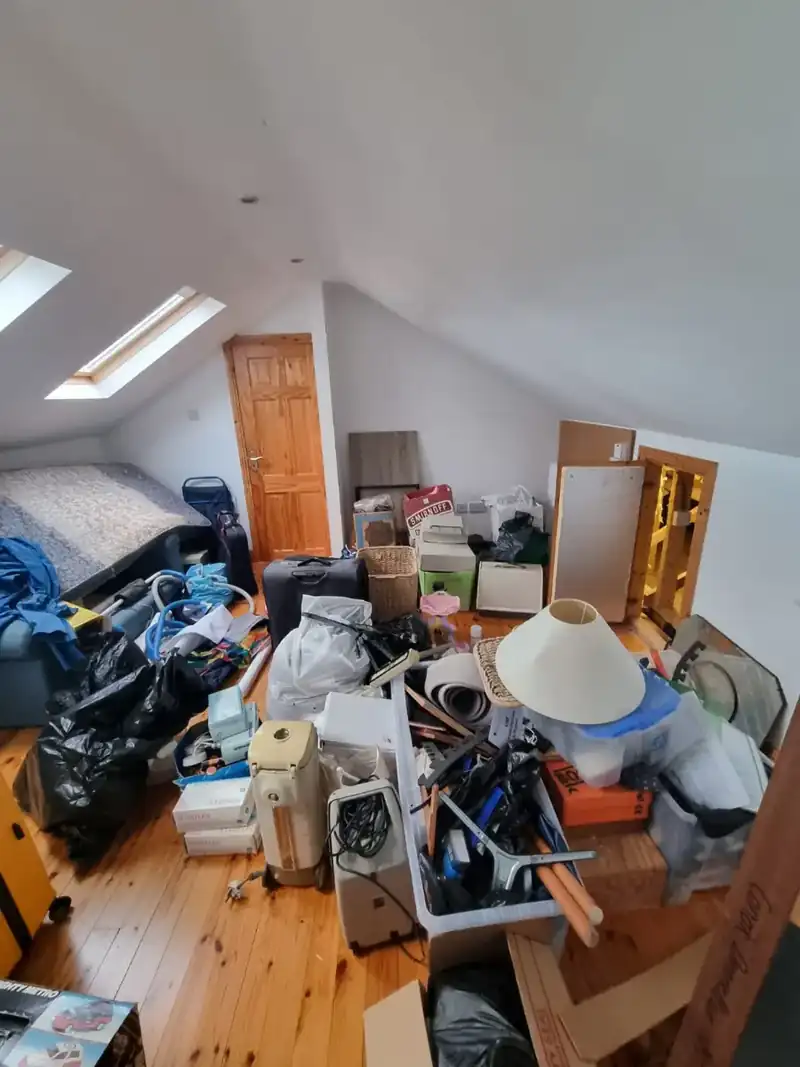 Attic bedroom full of bags, boxes and furniture before clearance