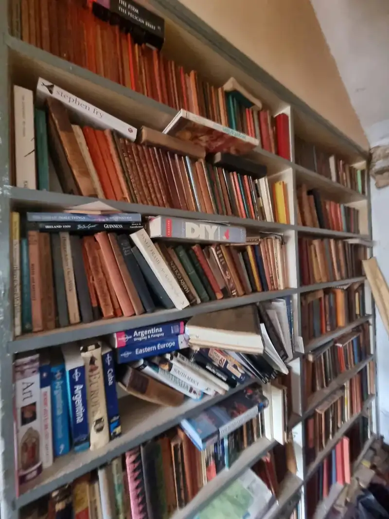 Shelves of books to be sorted, donated and removed during a house clearance