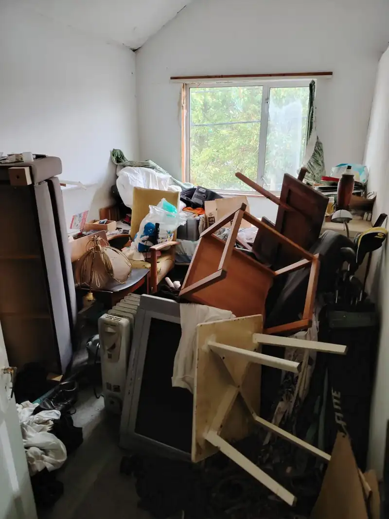 Room piled with chairs, boxes and belongings before clearance