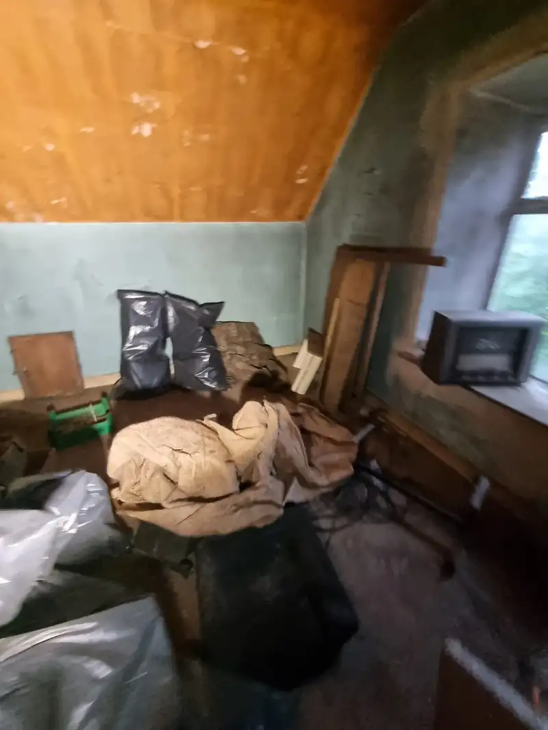 Cottage bedroom full of bags and belongings before a hoarder clearance