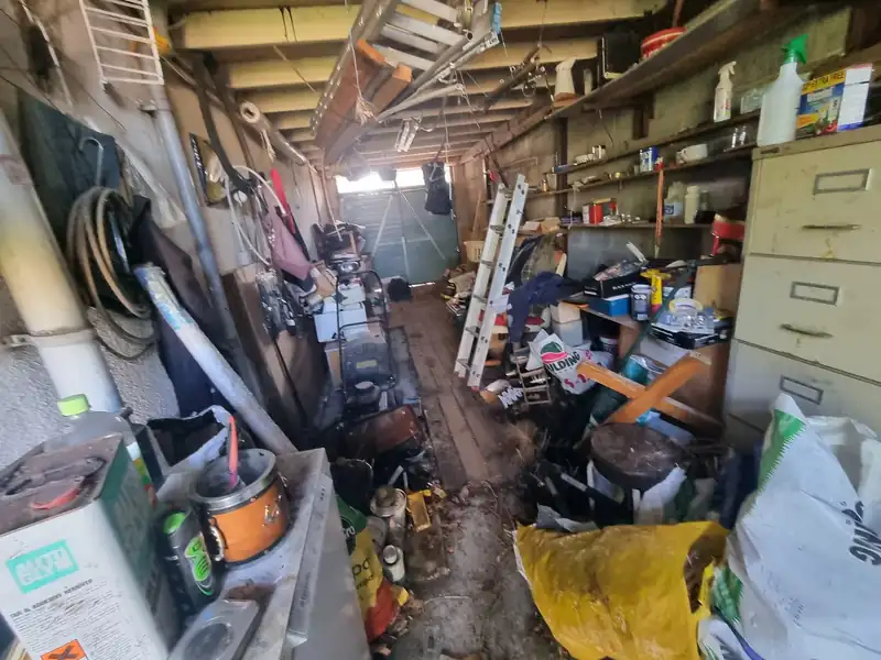 Garage workshop packed with tools, shelving and junk before a garage clearance