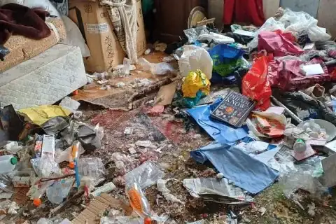 Room floor covered in rubbish and belongings before a hoarder clearance