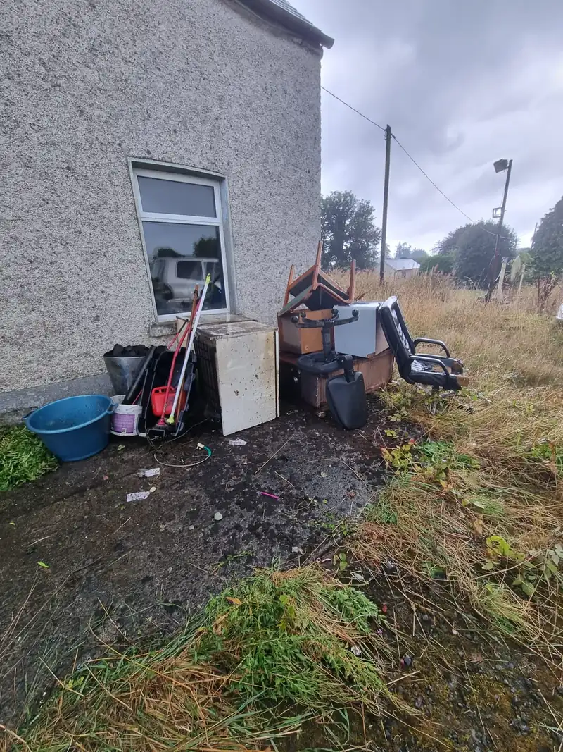 Rubbish and old appliances outside a rural property before clearance