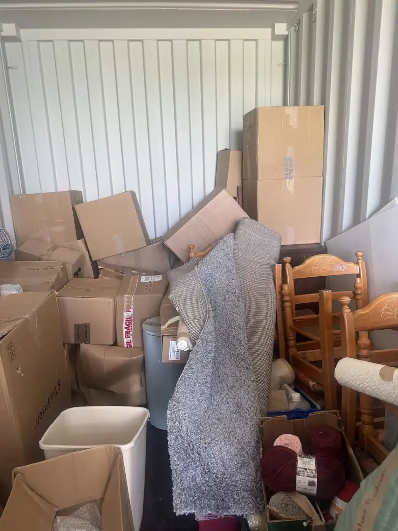 Storage unit packed with chairs, boxes and household items before clearance